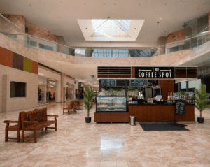 Southwestern shopping plaza with a white horse sculpture and a walk-up coffee kiosk under golden-hour light